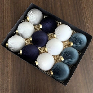 Close-up of 12 luxury velvet Christmas balls in navy and silver inside a black gift box