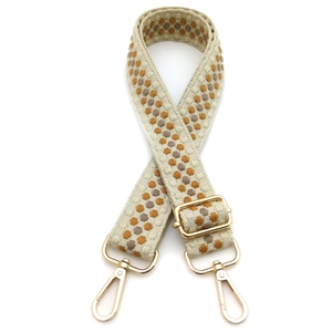 Detail of adjustable beige bohemian woven bag strap with golden metal lobster clasps