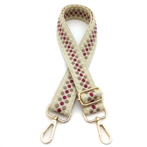 Detail of adjustable woven bag strap with red geometric pattern and gold swivel hooks