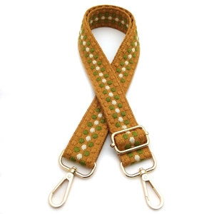 Detail of yellow woven bag strap with green polka dots and gold metal swivel snap hooks