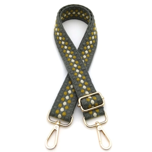 Detail of wide embroidered gray canvas strap with yellow polka dots and gold metal clips
