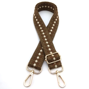 Detail of adjustable woven brown strap with vintage pattern and gold metal buckles