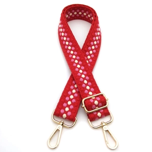 Close-up of thickened red woven strap with pink dots and golden metal buckles