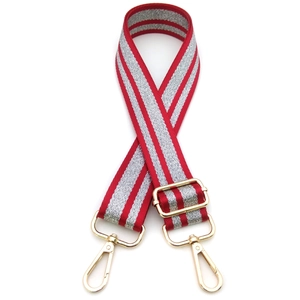 Close-up of red and silver grey striped canvas bag strap with golden metal lobster clasps