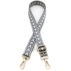 Detail of adjustable gray strap with white arrow pattern and gold metal swivel snap hooks