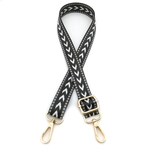 Detail view of adjustable black and white arrow pattern shoulder strap with gold metal hardware