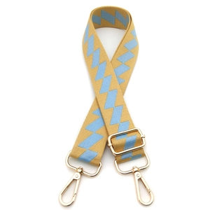 Macro detail of adjustable jacquard bag strap with geometric patterns and gold metal clips