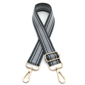 Detail view of adjustable black and white herringbone shoulder strap with gold metal hooks