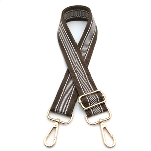Detail of adjustable brown and white woven shoulder strap with gold metal lobster clasps