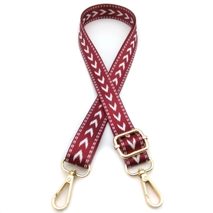 Detail of adjustable wine red woven bag strap with white arrow pattern and gold metal clips