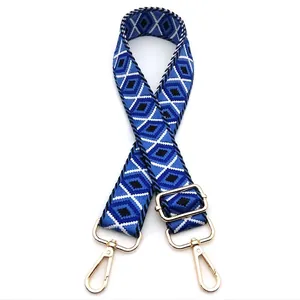 Detail of blue geometric diamond pattern adjustable woven bag strap with gold hooks