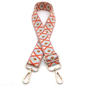 Detail of adjustable woven strap with orange geometric pattern and gold metal hooks