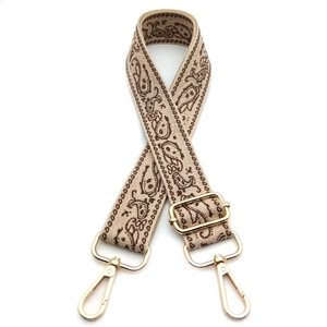 Detailed view of adjustable paisley pattern bag strap with polished gold metal hooks