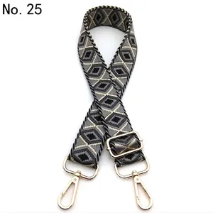 Detailed view of wide woven shoulder strap with geometric diamond pattern and gold hardware