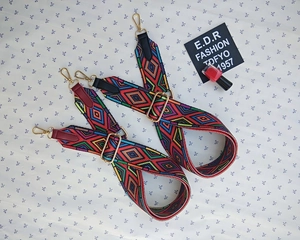 Close-up of ethnic style woven bag straps with colorful geometric embroidery and gold hooks