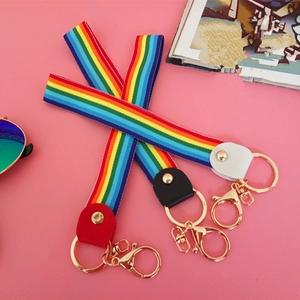 Detail of colorful rainbow woven wristlets with gold metal hooks on a pink background