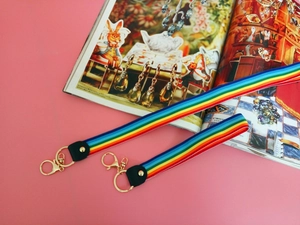 Close-up of rainbow striped lanyards with gold metal lobster clasps and black leather accents