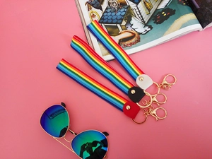 Detail view of woven rainbow keychains with colorful stripes and gold metal hardware