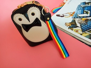 Detail of penguin mini coin purse with colorful rainbow wristlet strap and golden clasp