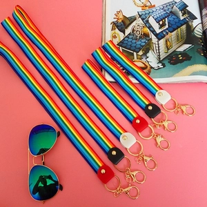 Rainbow striped woven keychain lanyard with golden lobster clasp on pink background