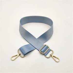 Close-up of light blue adjustable nylon bag strap with polished gold metal hardware