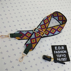 Detail of colorful geometric woven bag strap with golden lobster clasps and leather ends