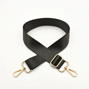 Detail of adjustable black woven nylon bag strap with polished gold lobster clasps