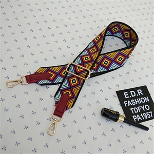 Detail of adjustable bag strap with ethnic geometric pattern and golden metal buckle