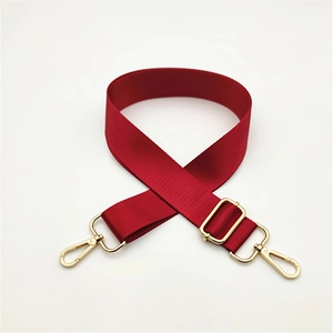 Detail of red nylon shoulder strap with golden metal swivel lobster clasps and buckle