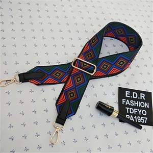 Detail view of ethnic geometric pattern wide strap with gold metal hooks and black leather ends
