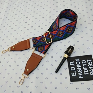 Detail of colorful geometric wide bag strap with brown leather ends and gold metal buckle