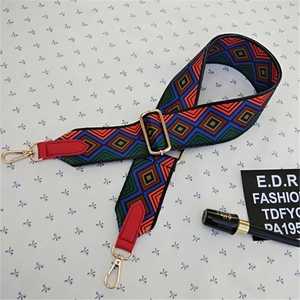 Detail view of colorful geometric woven bag strap with red leather ends and gold metal hooks