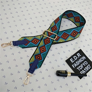 Close-up of adjustable woven shoulder strap with colorful geometric diamond pattern and gold hooks