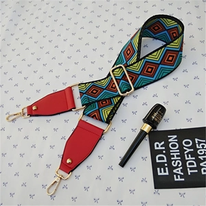 Detail of colorful geometric woven strap with red leather ends and gold metal clasps