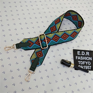 Detail view of ethnic style woven bag strap with colorful patterns and gold metal hooks
