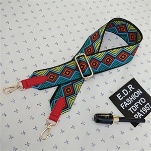 Detail of adjustable woven bag strap with geometric diamond patterns and gold buckles