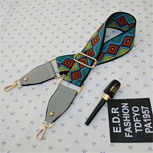 Detail of adjustable crossbody strap with colorful geometric rhombus weave and gold hooks