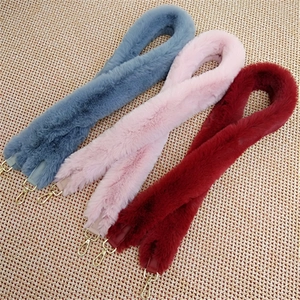 Detail view of plush faux fur bag straps in blue, pink, and red with gold metal clasps