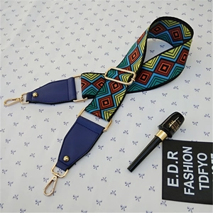 Macro view of geometric woven wide handbag strap with gold buckle and leather detail