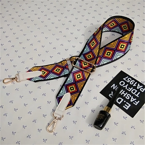 Detail of colorful geometric woven shoulder strap with white leather and gold metal hooks