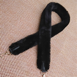 Detail of plush black faux fur bag strap with gold metal buckles and leather ends