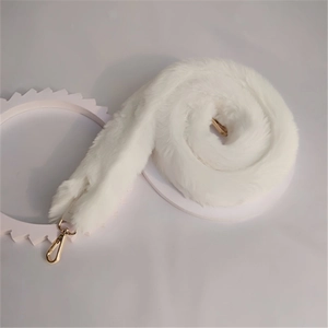 Detailed macro view of a fluffy white faux fur bag strap with gold metal lobster clasps