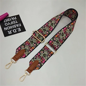 Close-up of adjustable ethnic floral pattern bag strap with gold metal hook and leather trim