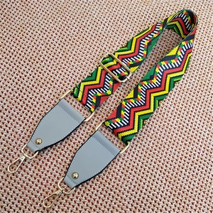 Detail of ethnic style woven bag strap with colorful wave pattern and gold metal buckles