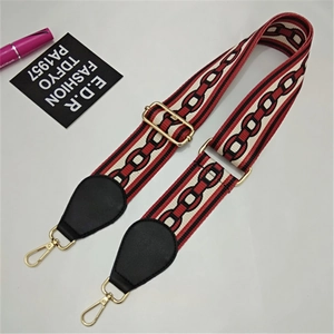 Detail of adjustable wide woven bag strap with geometric patterns and gold lobster clasps