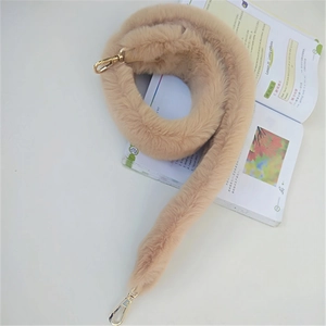 Detail of soft beige faux fur shoulder strap featuring elegant gold metal lobster clasps