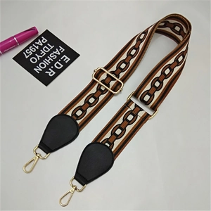 Macro view of adjustable woven bag strap with geometric chain pattern and gold buckles