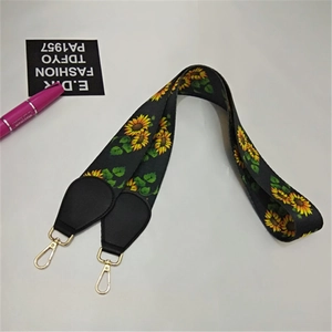 Detail of sunflower pattern webbing strap with black leather ends and gold lobster clasps