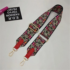 Detail of ethnic floral embroidery shoulder strap with red leather ends and gold buckle