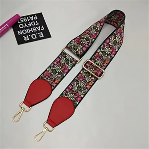 Detail of adjustable wide shoulder strap with floral embroidery and golden metal hooks